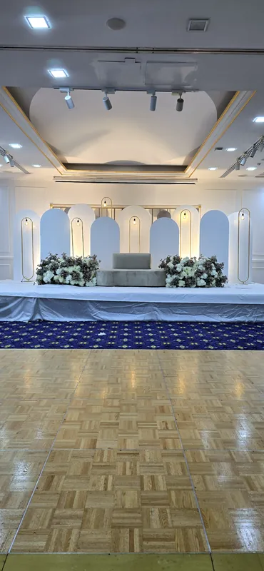 Ballroom stage with a white arcade, flowers and a blue carpet