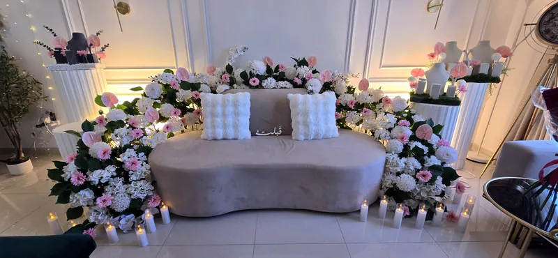 Vue large d’un salon fleuri avec des roses sur colonnes et des lanternes