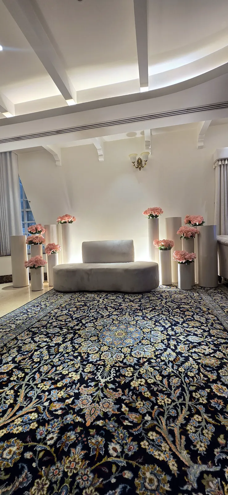 Sofa with pink flower pillars on a patterned blue carpet