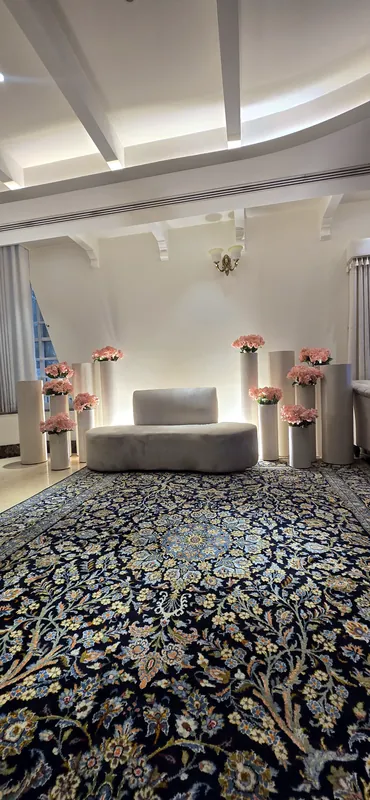 Sofa with pink flower pillars on a patterned blue carpet