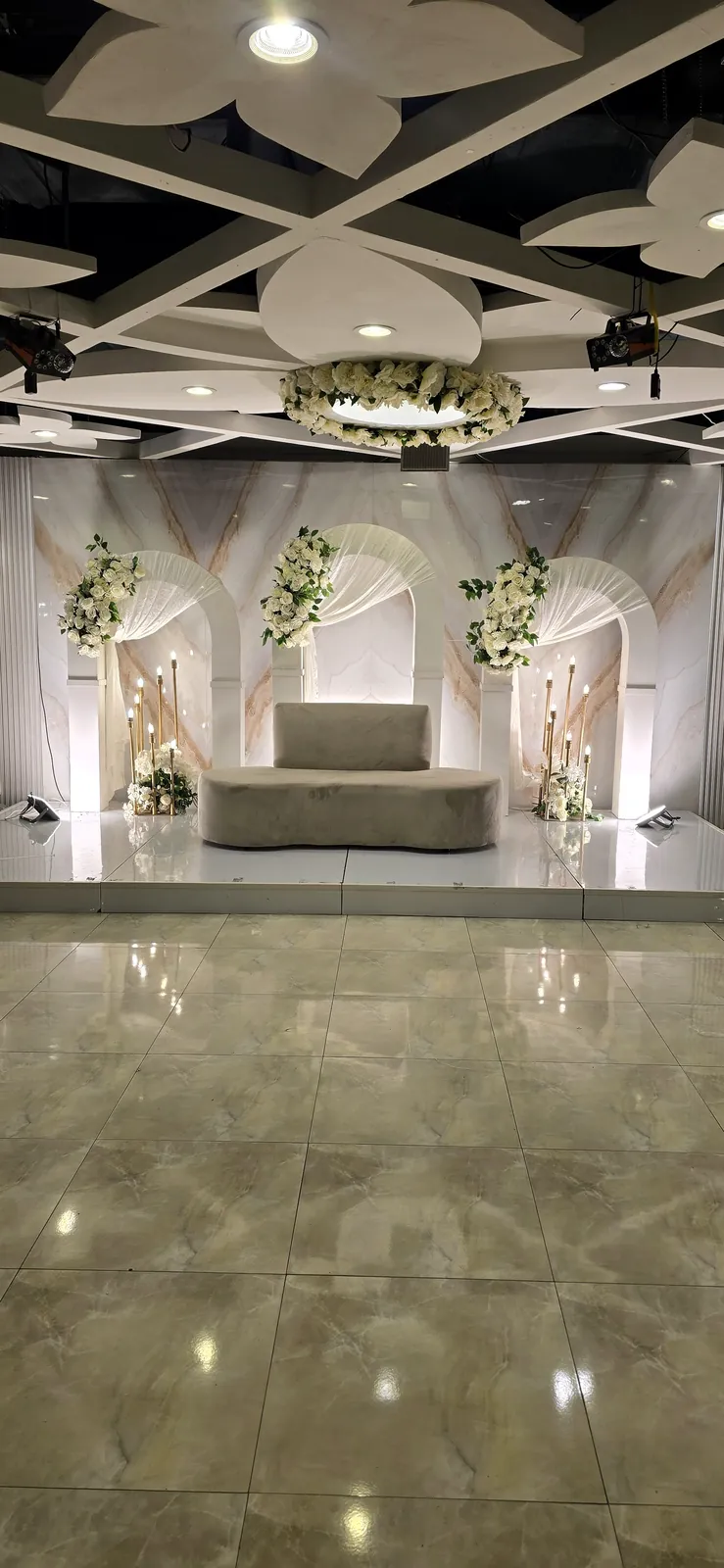 Stage sofa under a lit ceiling with flower arches and a glossy floor