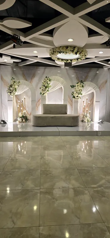 Flower arches and a sofa on a stage beneath a hanging floral ring