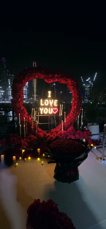 Glowing love sign and roses on a deck at night
