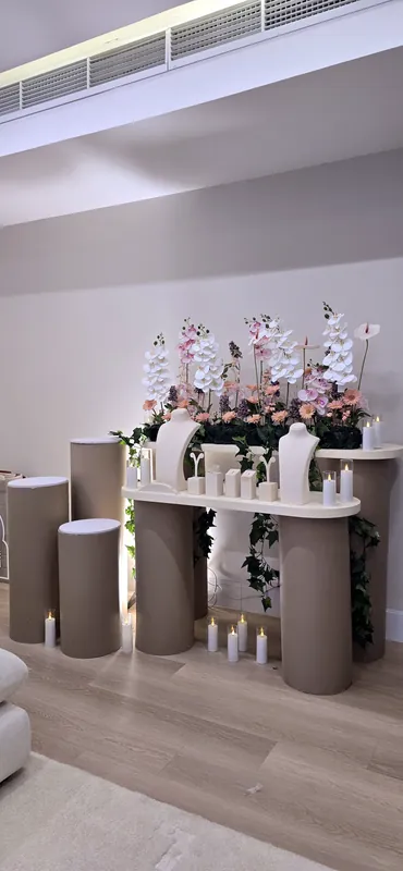 Orchid display with candles at the foot of taupe pedestals