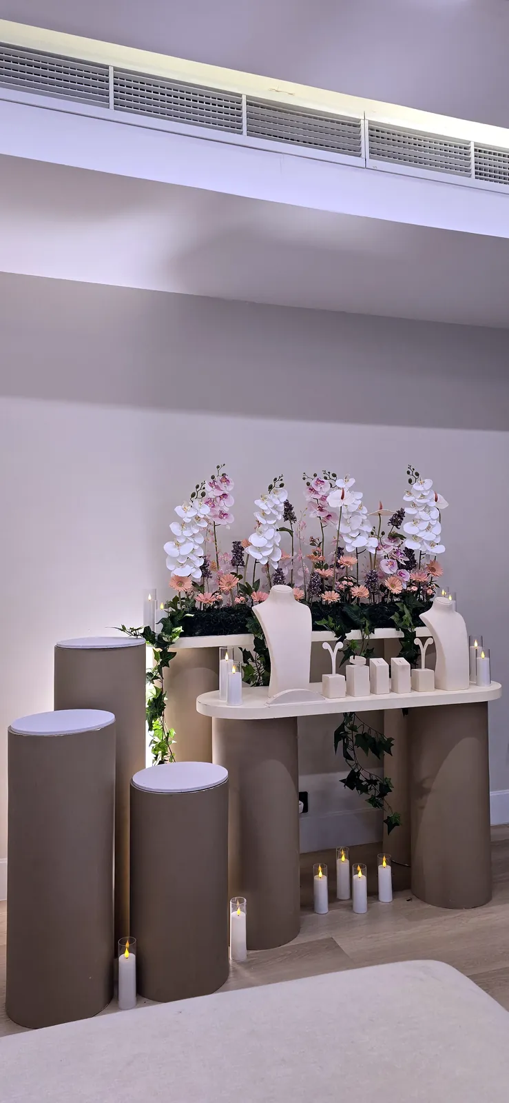 White orchids on a console with candles and soft taupe pillars