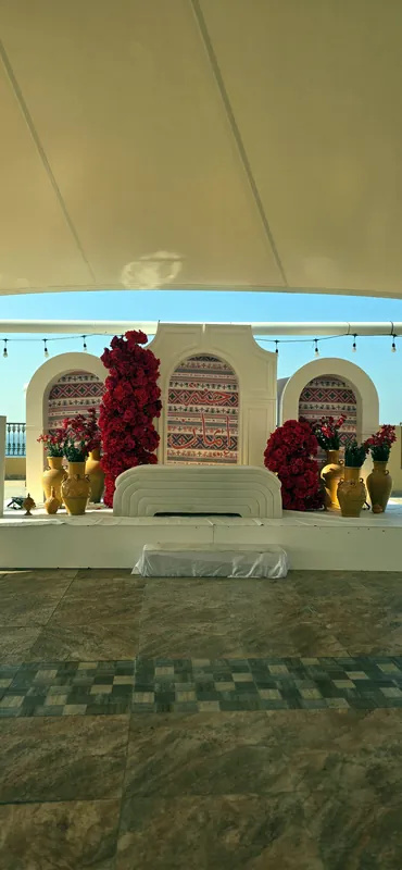 Arches à motifs avec fleurs rouges et vases en laiton sur une scène extérieure
