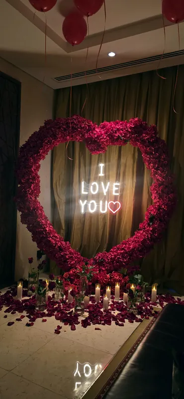 Lit sign framed by a red rose heart in a softly lit room