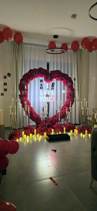 Cœur de roses, panneau I love you et bougies dans une pièce aux ballons rouges