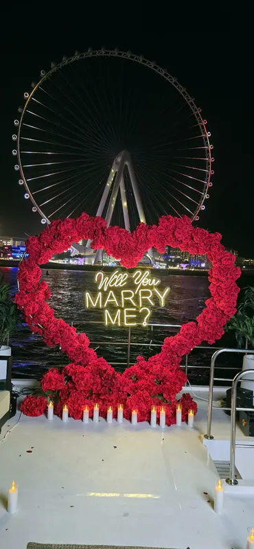 Candles lining a red rose heart on a yacht deck at night